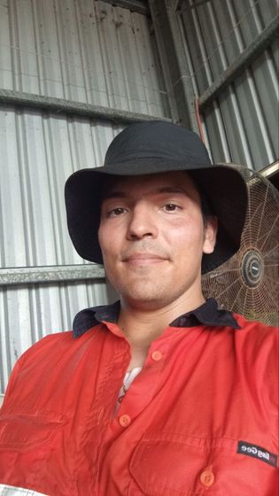 David in a hi-vis work shirt and wide-brim hat in a farm shed